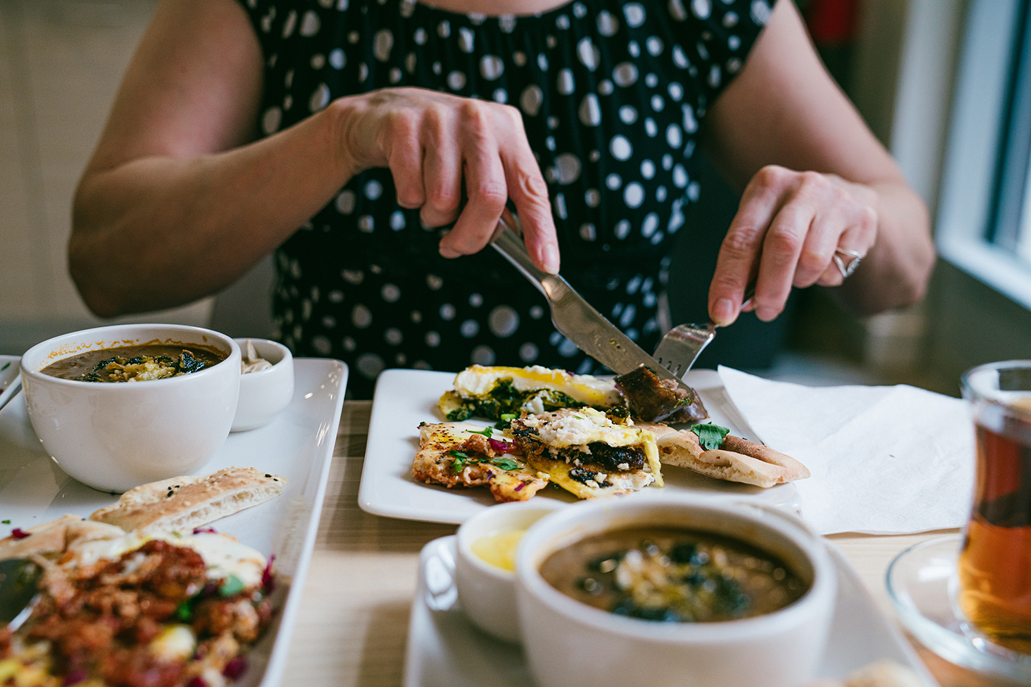 A woman uses her fork and knife to cut into a weekend brunch at Botte Chai Bar in Saskatoon Saskatchewan.